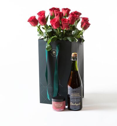 Røde roser i gavepose med bobler og sjokolade